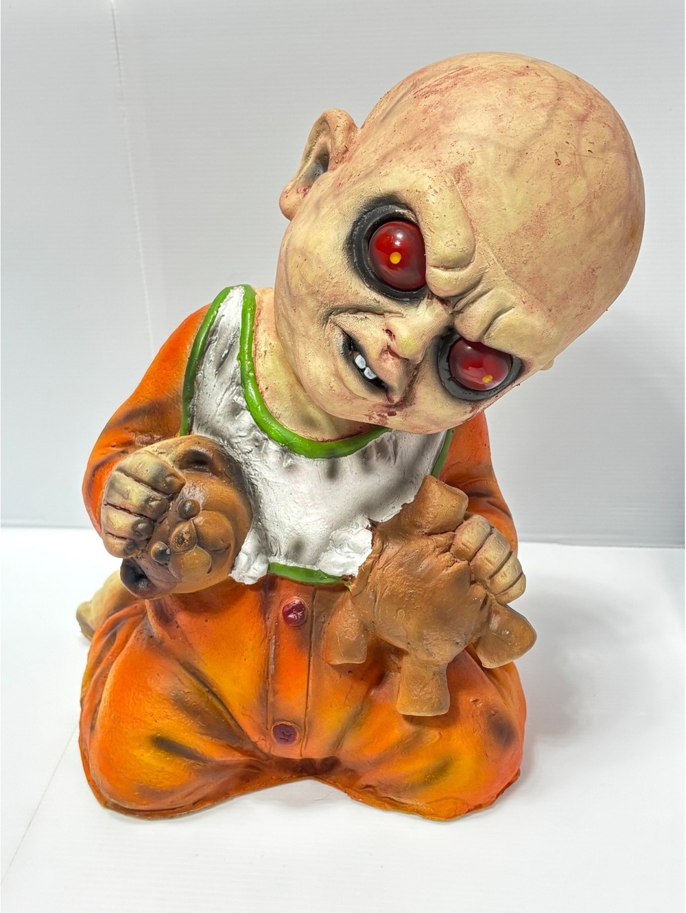 Creepy Horror Baby Figurine with Red Eyes Holding Teddy Bears in Orange Outfit